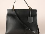 a black leather handbag with a strap and a tag on the front