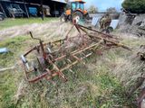 un tracteur immobilisé dans l'herbe, avec une charrue attelée derrière lui