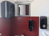 une salle de bains équipée d'un lavabo, d'un miroir et d'un distributeur de savon