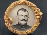 une vieille photo d'un homme moustachu dans un cadre doré