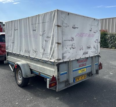 un camion dont l'arrière est recouvert d'une bâche, garé sur un parking