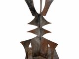 La sculpture est en métal et présente un motif géométrique.
