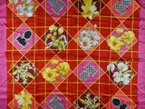 a close up of a red and yellow quilt with flowers on it