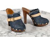une paire de sabots en jean bleu à talon en bois posée sur une table en marbre