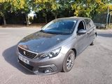 La voiture argentée est garée sur le parking près des arbres.