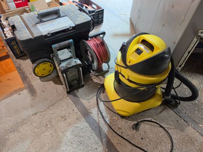 un aspirateur jaune et noir posé par terre à côté d'une boîte à outils