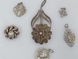 several silver and gold jewelry pieces including a pendant, broochle, and a broochle