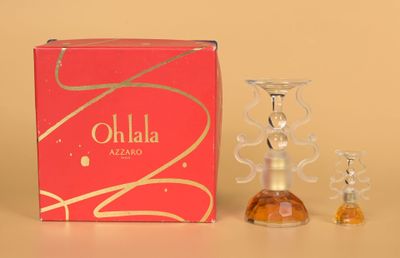 un petit flacon de parfum posé à côté d'un petit photophore en verre