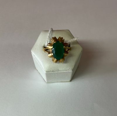une bague sertie d'une pierre verte, posée sur une boîte blanche