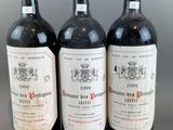 three bottles of red wine are lined up on a table