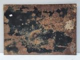 rusted metal plate on a white wall with a piece of paper attached to it