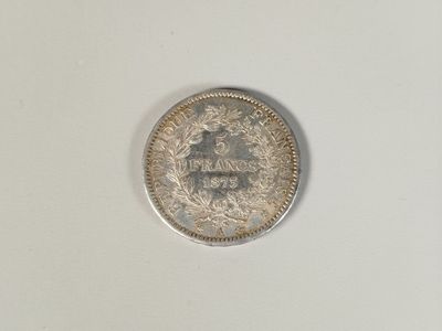 une vieille pièce d'argent posée sur une surface blanche