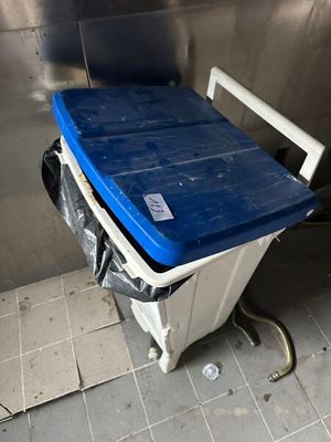 une poubelle bleue et blanche posée dans un coin d'une pièce