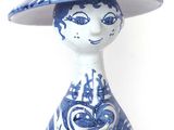 a blue and white figurine of a woman wearing a hat