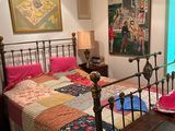a bed with a quilt on it and a painting on the wall
