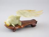 figurine sculptée représentant un poisson ailé, posée sur un socle en bois