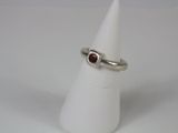 silver ring with garnett stone on top of a white cone