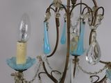 a chandelier that has a candle and some blue glass beads hanging from it