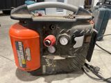 un compresseur d'air orange et noir posé sur un sol en béton