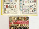 un livre ouvert posé sur une table, à côté d'un livre contenant des timbres