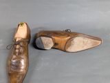 pair of brown leather shoes with laces on them on a gray surface