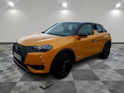Le SUV orange est garé dans une grande pièce au sol carrelé en damier.