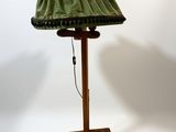 a lamp that is on a wooden stand with a green shade
