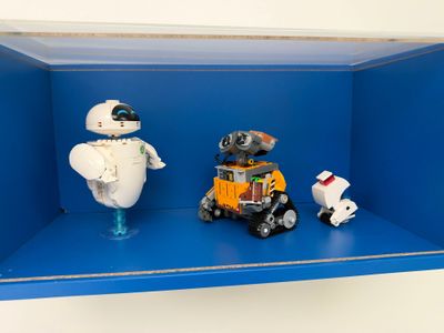 deux robots posés sur une étagère bleue avec une petite voiture