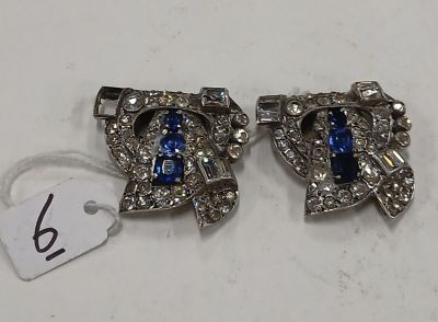 une paire de boucles d'oreilles « Rhine » bleues et blanches posées sur un fond blanc