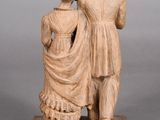 statue of a man and a woman standing next to each other on a wooden base