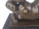 a bronze statue of a woman laying down on a black base