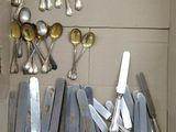 a lot of silver spoons and knives in a box