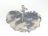 a silver figurine sitting on top of a leaf shaped plate