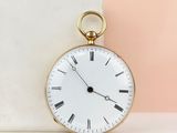 une montre de poche en or posée sur un bloc de marbre