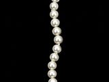 a white pearl necklace with a gold clasp on a black background
