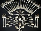 un grand nombre de cuillères et de fourchettes en argent disposées en cercle