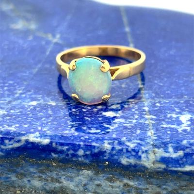 a close up of a gold ring with a white oplite stone