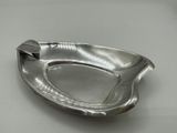 a silver ashtray on a table with a spoon in it