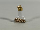 a small glass bottle filled with gold colored beads
