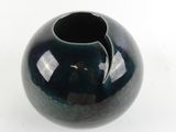 a black vase with a hole in it on a white surface