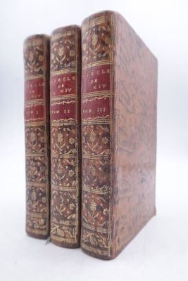 three old books sitting on top of each other on a white surface