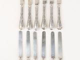 six silverwares on a white table with a knife