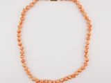 an orange beaded necklace on a white background