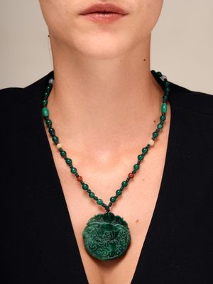 un gros plan d'une femme portant un collier orné d'un pendentif vert