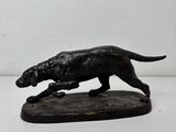 statue d'un chien en train de courir, posée sur un socle en bois, sur fond blanc