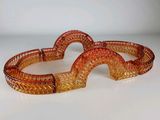 deux bracelets en verre orange posés sur une surface blanche, sur fond blanc