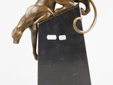 bronze sculpture of a cat on a black base with a white background