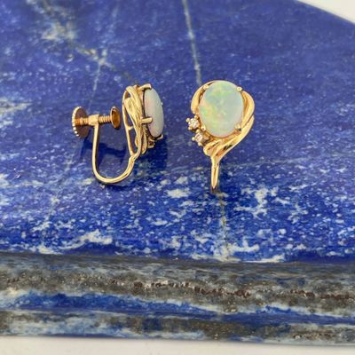une image représentant une paire de boucles d'oreilles « oplite » posées sur une pierre bleue