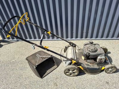 a lawn mower that is sitting on the ground next to a trash can