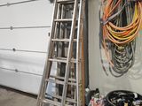 une échelle appuyée contre le mur d'un garage, à côté d'une poubelle